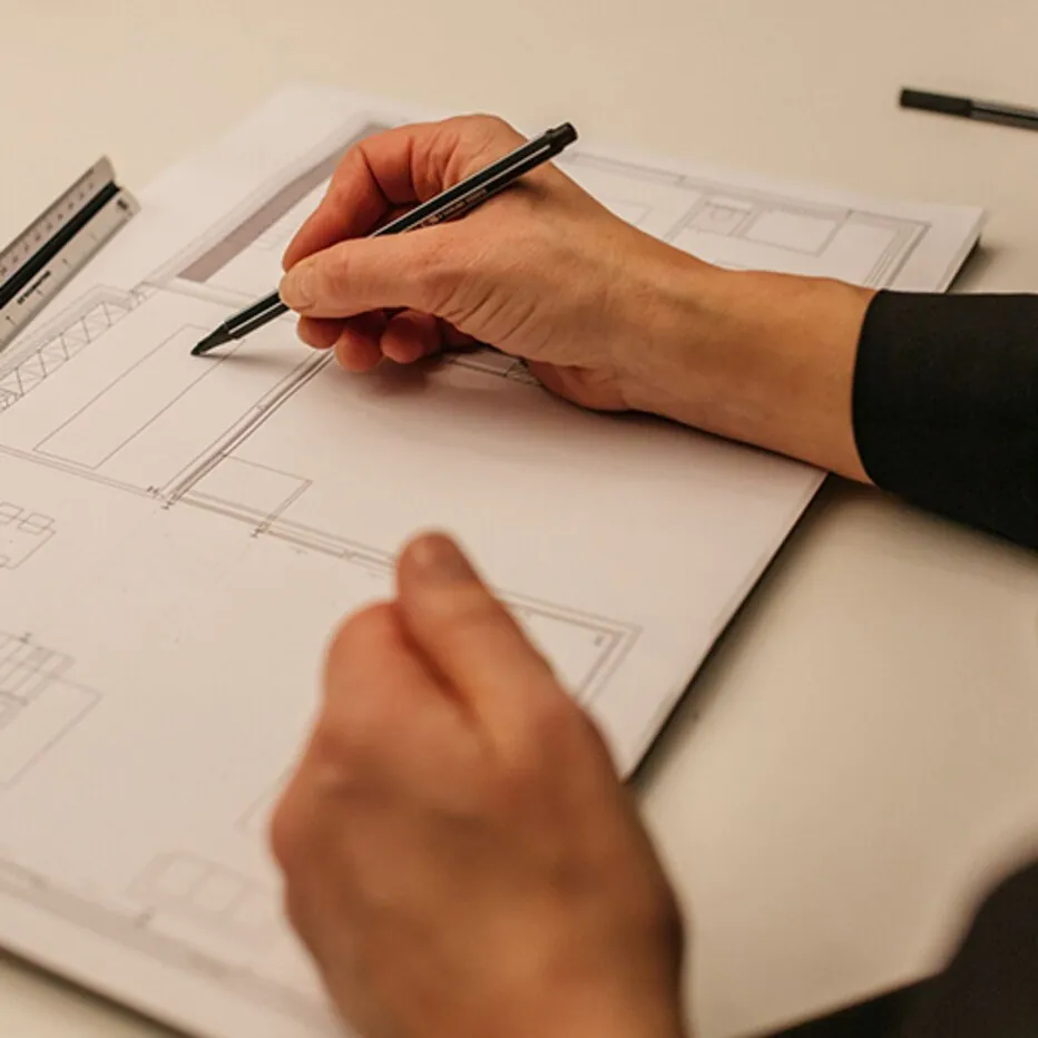Coulisses : une main dessine un plan (inspiration Occhio)