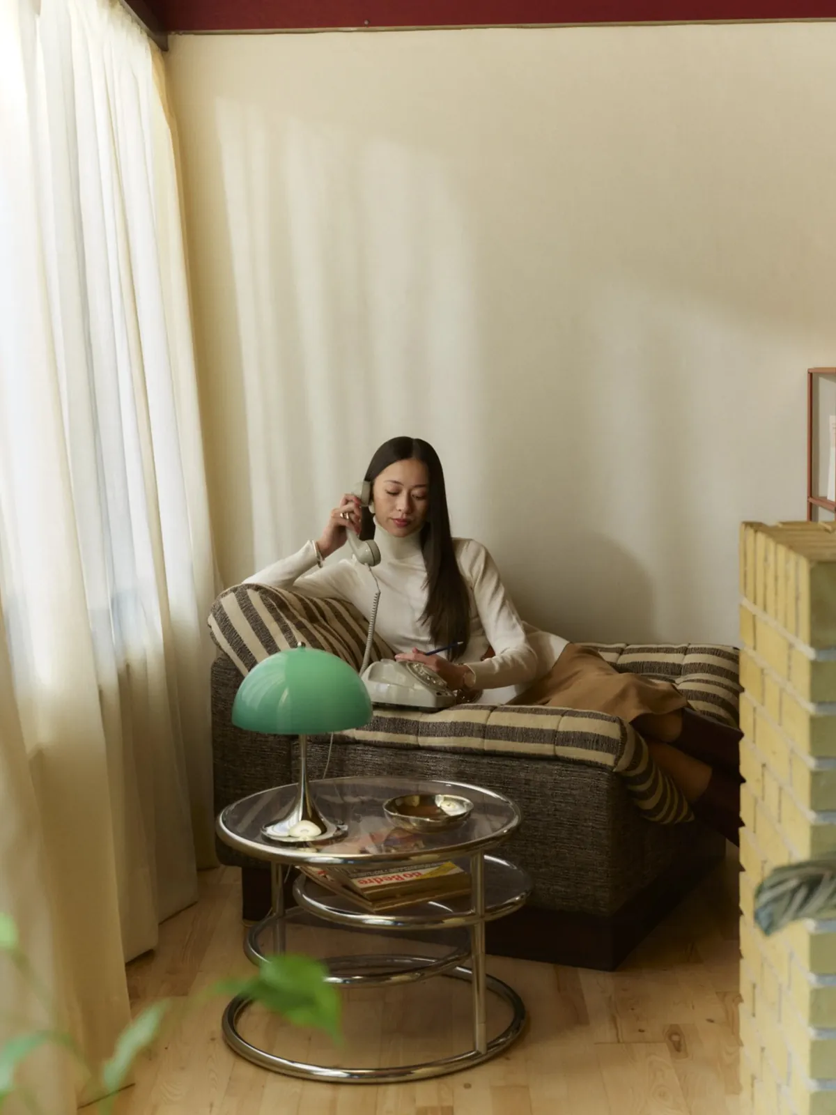 Lecture dans un fauteuil, la lampe en premier plan (inspiration Louis Poulsen)