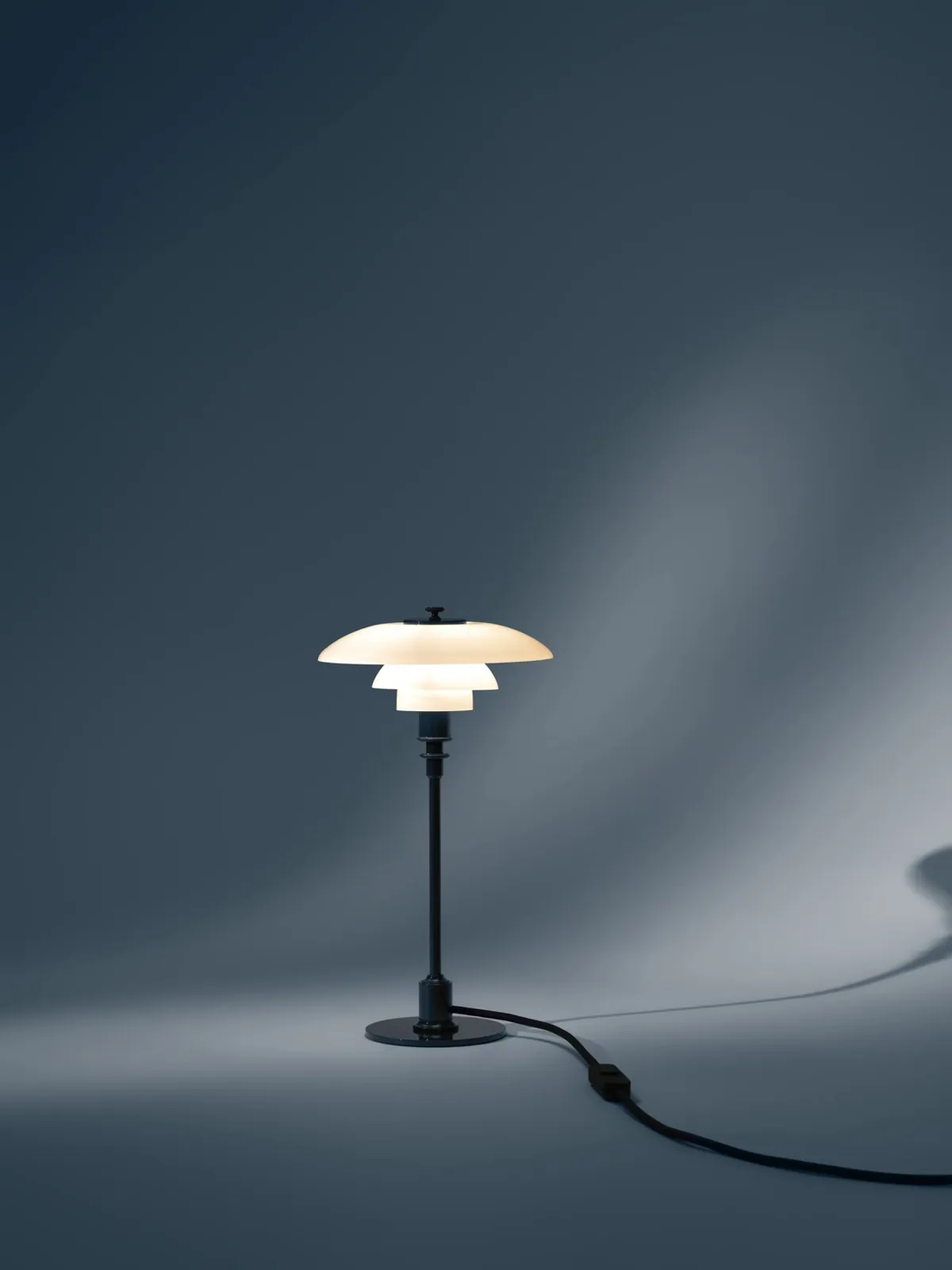 Lampe allumée sur un fond bleu-gris (inspiration Louis Poulsen)